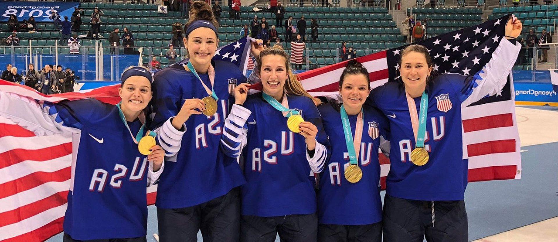 Women's hockey players holding an American flag