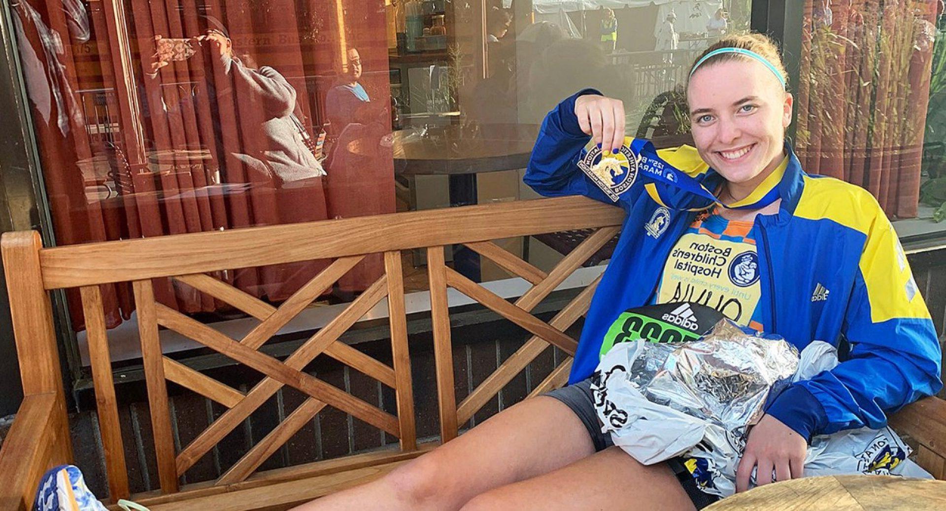 Olivia Colombo sitting on a bench holding a medal